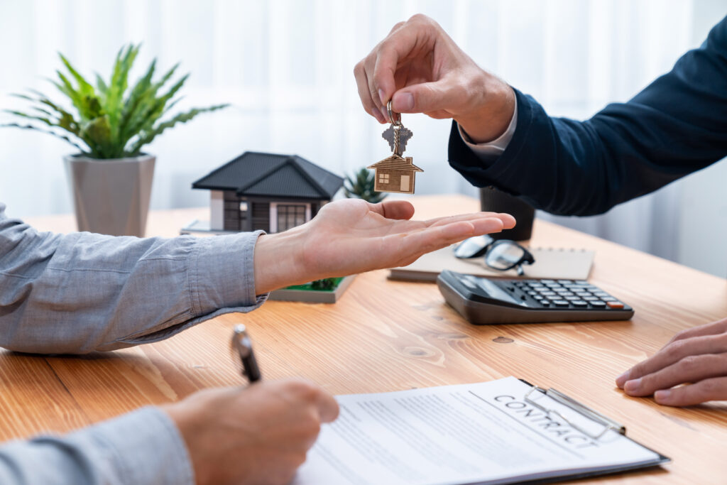 Real estate agent handing house key to buyer after signing rental lease.